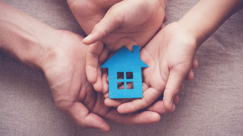 duas mãos seguram uma casa para habitação acessível